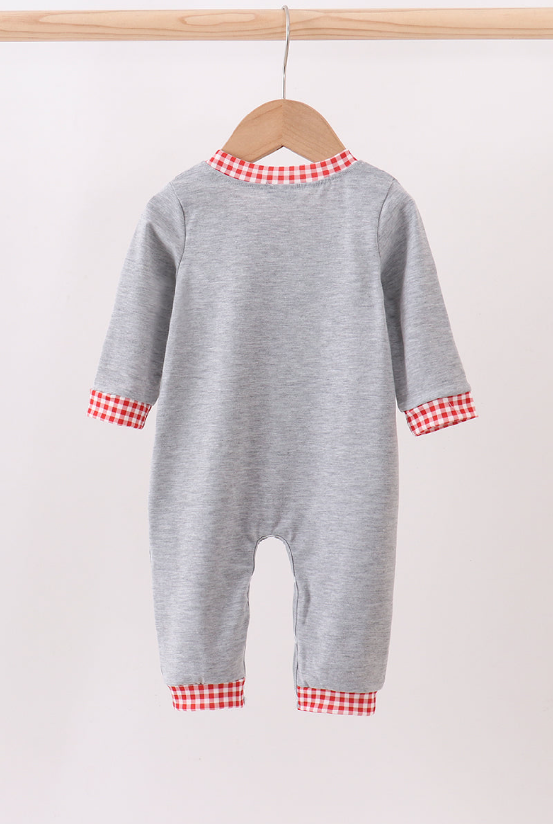 Gray baby onesie with red and white checkered trim on a wooden hanger against a white background