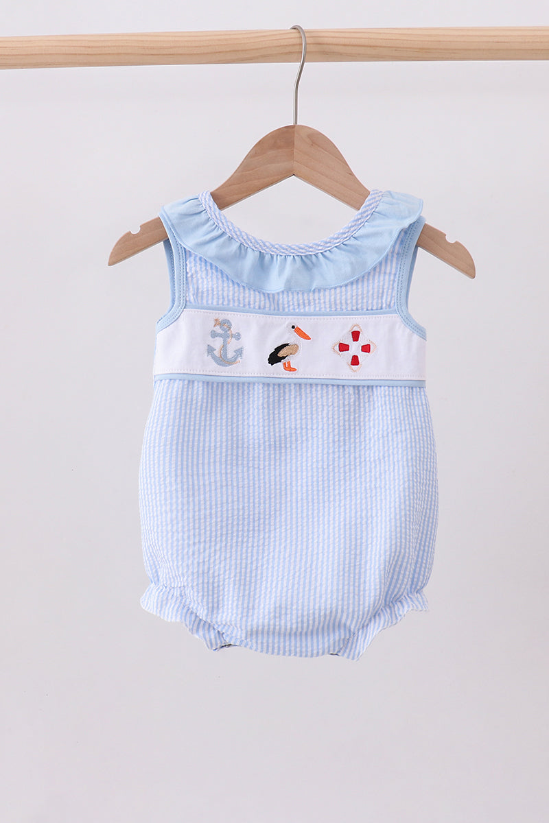 Baby romper with nautical design on a hanger against a plain background