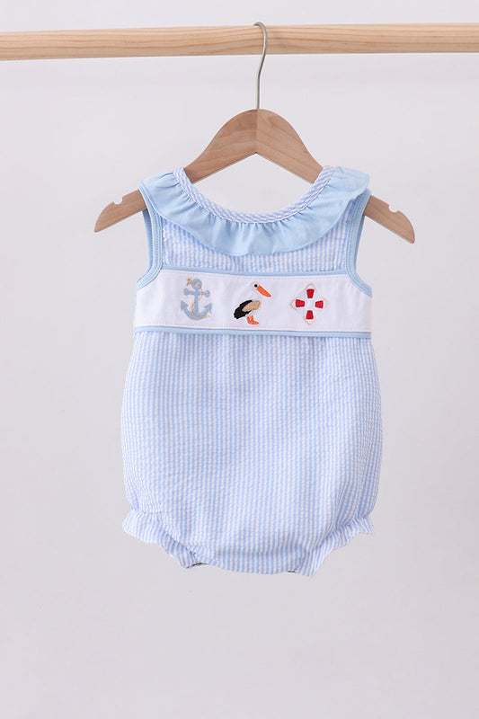 Baby romper with nautical design on a hanger against a plain background